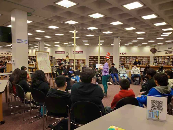 Librarian Ms. Neal reads a story book to the class while wearing a Cat in the Hat hat
