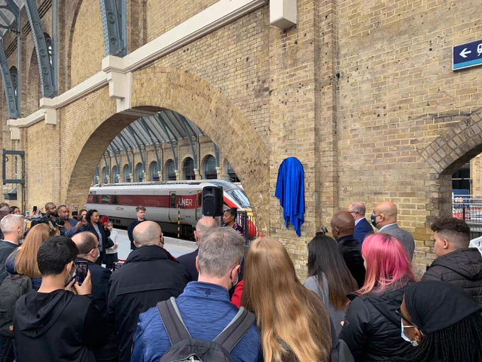 A crowd gathers before the plaque before the unveiling