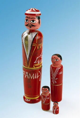 Houten speelgoed, rood gelakt. Een vader met daarin drie kleinere popjes die moeder en twee kinderen voorstellen.
