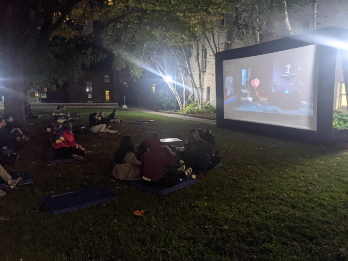Students gather in the quad at St. Michael's to watch a Halloween movie in the evening outdoors 
