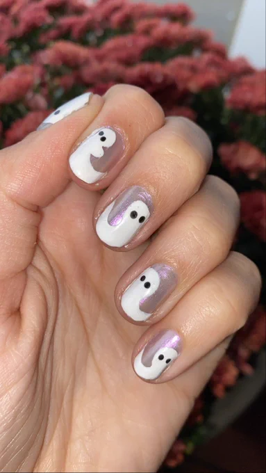 A hand with nails painted chrome purple with little ghost design