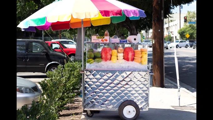 a fruit vendor cart on a sidewalk