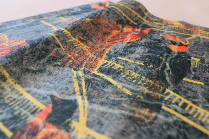 Penfia Rodrigues
ID: A close up image of a charcoal coloured fabric printed with bright yellow, orange and black birds and patterns.