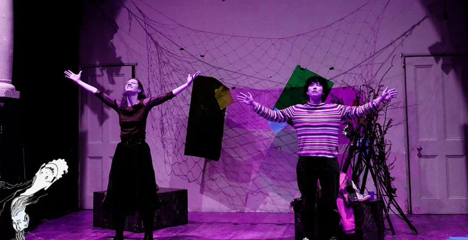 A production photo from To be a bat. Two young people stand with their arms outstretched and their eyes closed, as if summoning something. 
