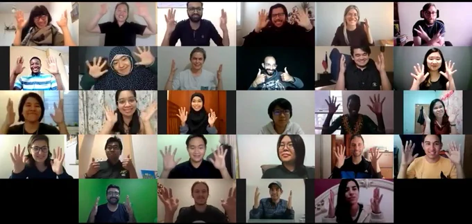 Screenshot of Zoom meeting of 28 people. Most of them are waving their hands.