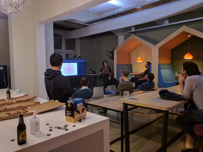 Photo of a group of people looking at screen containing generative art