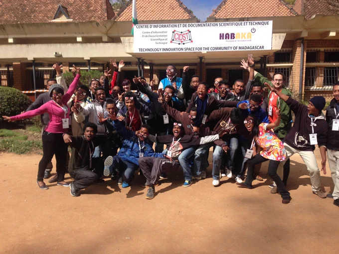 A group of over two dozen people happily shouting at the camera posing in front of Madagascar's Habaka tech space.