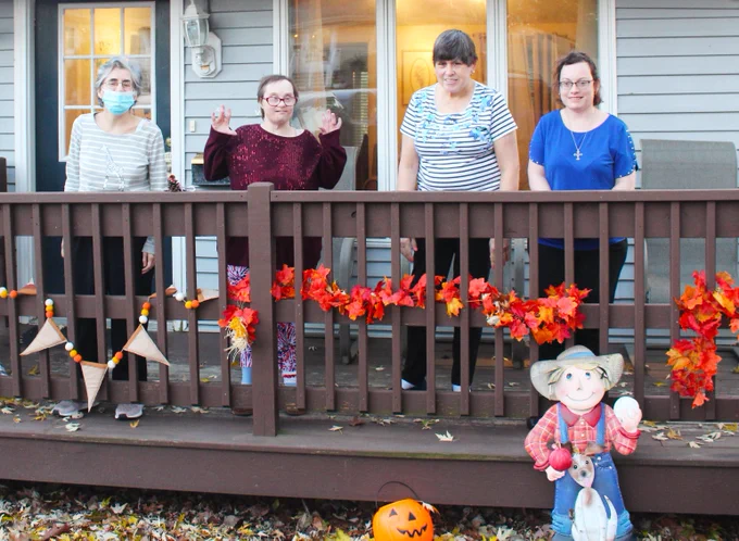women smiling in front of home decorated for fall