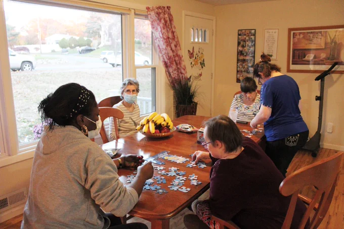 women working on puzzles with staff at the kitchen table