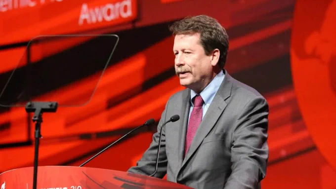Robert Califf speaking at a podium in front of a colorful background