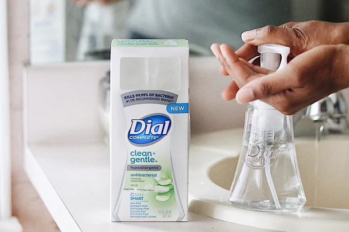 Woman uses Dial Clean   Gentle Aloe Foaming Hand Wash at a bathroom sink.