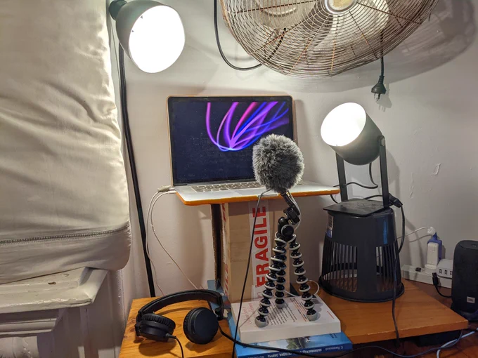 Laptop, lights and microphone set up in an improvised manner to make a home recording studio.