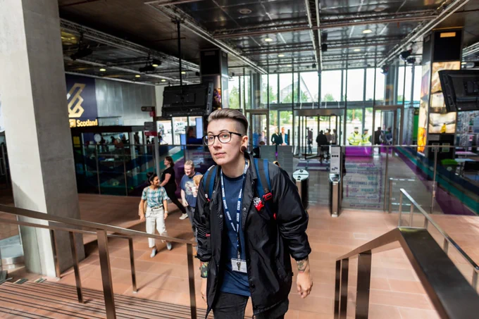Employee walking up a flight of stairs into the BBC offices in Glasgow, Pacific Quay.