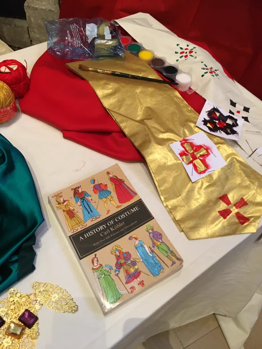 A book on the history of costume along with some gold cloth, some red cloth, fabric paints and gold and red thread.