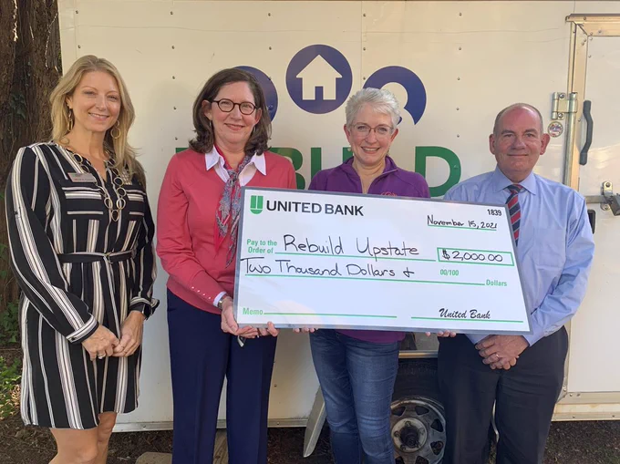 United Bank employees pose with a Rebuild Upstate employee. They show a large check featuring a $2,000 donation.