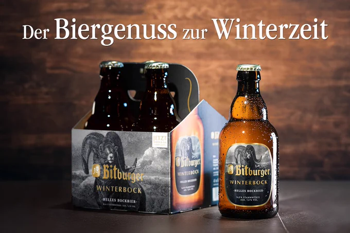 Bitburger Winterbock als Flaschen und in einem Vierer-Tray vor einem Hintergrund aus Holz in dunkler Atmosphäre. 