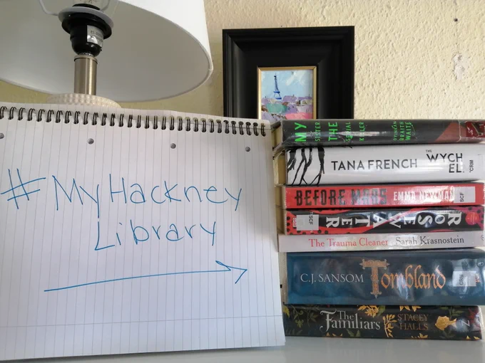a book shelf with a pile of books and a my hackney library sign