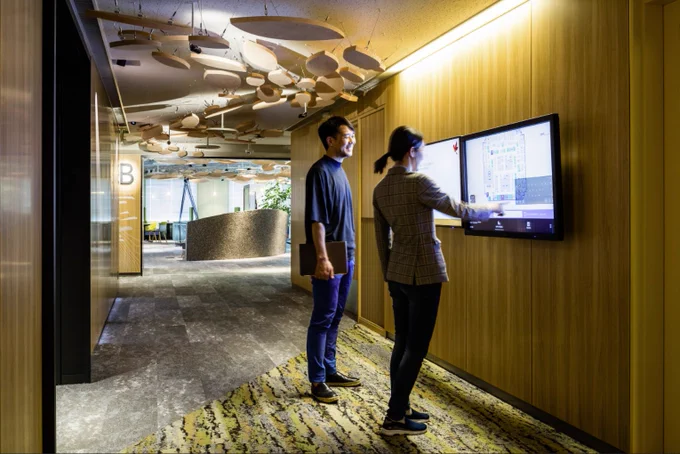 Two people stand in front of a touch screen at Microsoft Tokyo-Shinagawa.