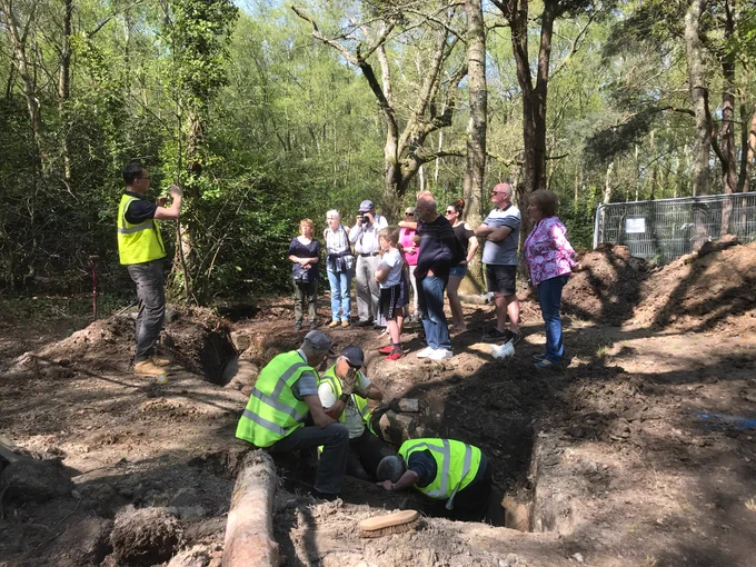 Group of people at a dig using digital devices 