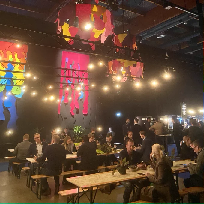 People sitting at tables with colorful lights above their heads.