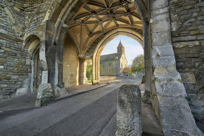Looking south through the stone gatehouse archway to St Mary's Church on an overcast day.