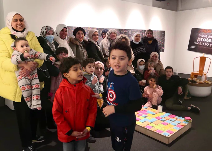A gallery with women and children gathered to face the camera, smiling