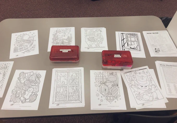 A table displaying Winter themed coloring pages and word find worksheets, as well as two boxes of coloring materials