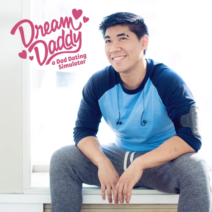 Cosplay of me as Craig Cahn from Dream Daddy (blue baseball tee, grey sweat pants, headphones off the neck, phone case strapped to arm, notched eyebrow). Giving a great, award winning smile while kind of sitting down, leaning slightly forward. Mega cute. "Dream Daddy - a Dad Dating Simulator" logo is in the top left.