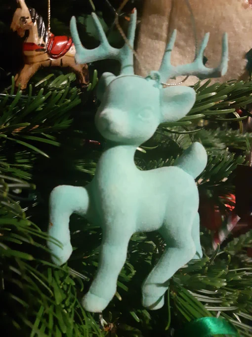 A turquoise reindeer decoration on a Christmas tree