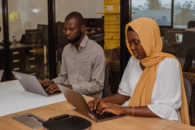 Two software engineers with their laptops, coding.