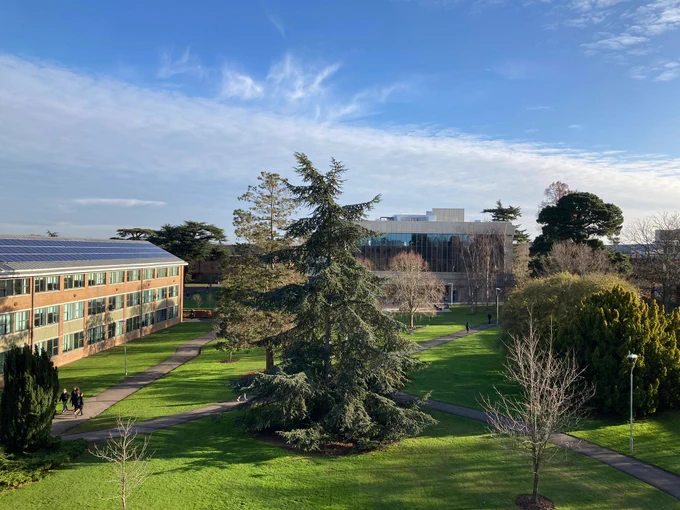 view of the centre of Whiteknights campus, with trees and solar panel-covered buildings under a bright blue sky