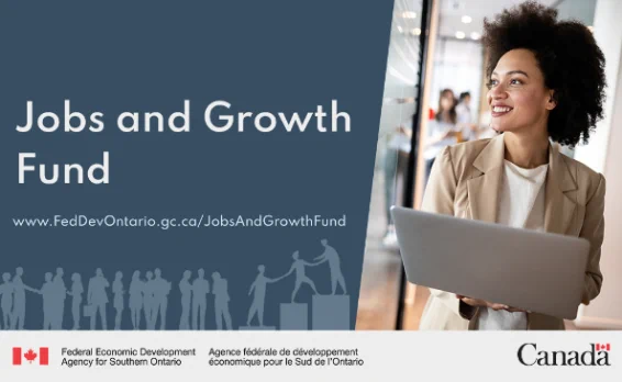 A businesswoman smiling while standing by windows in office. Text says Jobs and Growth Fund www.FedDevOntario.gc.ca/JobsAndGrowthFund