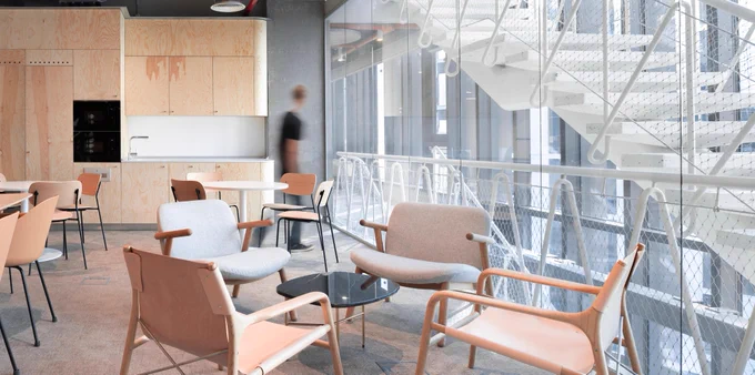 Casual work area at Microsoft Bucharest with numerous arm chairs surrounding tables.