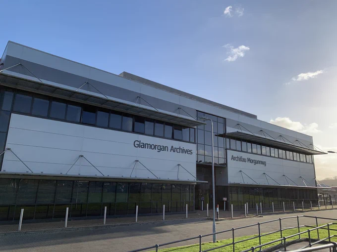 Blue skies behind a long white building with rows of windows. Black text tells you this is Glamorgan Archives.
