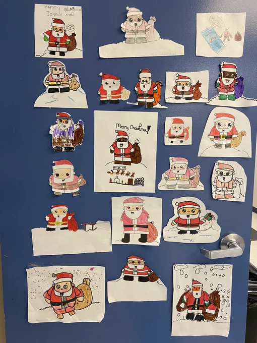 Classroom door covered with drawings of Santa in a variety of skin tones.