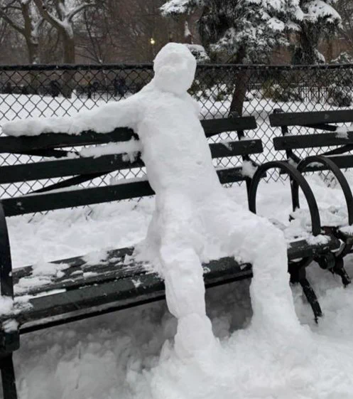 A snowman sitting on a park bench