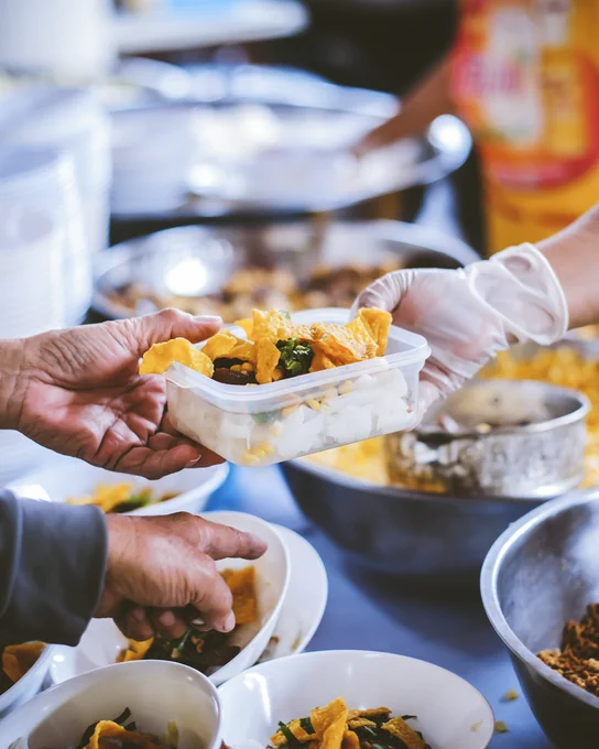 Image of food being put in container to go.