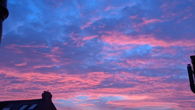 Deep pink coloured clouds against a blue sky at dawn