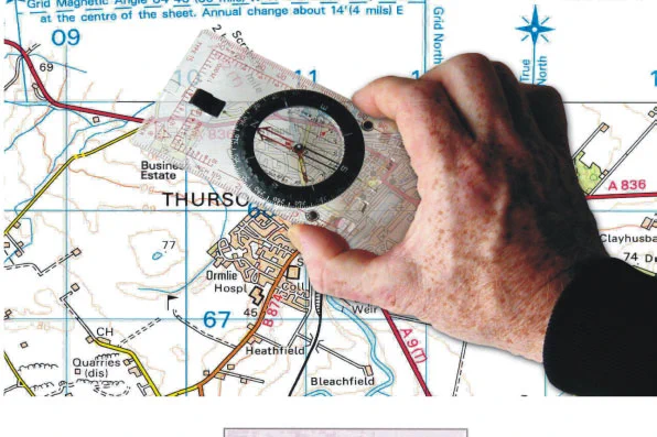 The hand of a man is holding a compass over a map. 