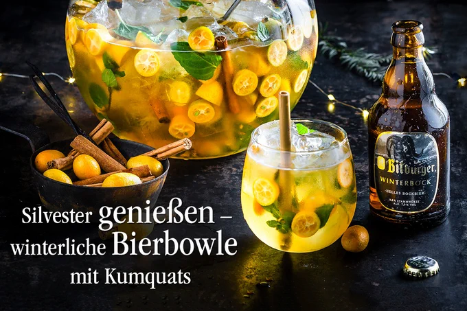 Bitburger Winterbock neben Winterbock-Bowle mit Kumquats auf festlich dekorierter Tafel.