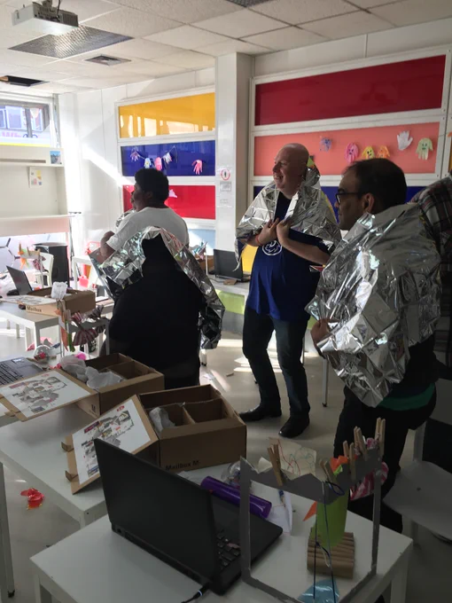 A group of four people looking towards a screen. They are dressed in silver home-made costumes.