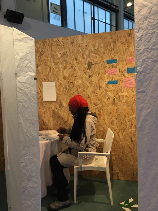A woman sits alone at a desk writing