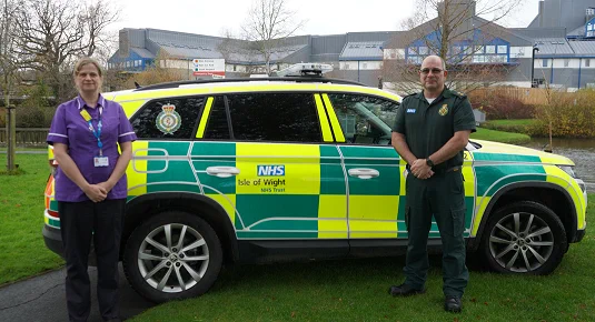 Image of ambulance vehicle with two members of staff standing in front of it