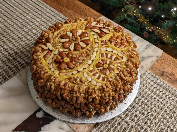 A homemade Christmas cake decorated with almonds and walnuts arranged in a paisley pattern