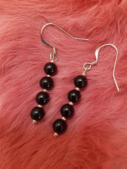 dainty earrings on pink dyed rabbit fur. the earrings are round black beads with rose gold seed beads in between. there are 4 black round beads and 5 rose gold seed beads.