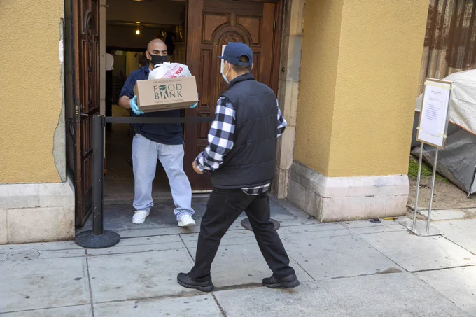 LA Regional Food Bank Partner Agency hands food kits to a food recipient during a food distribution.
