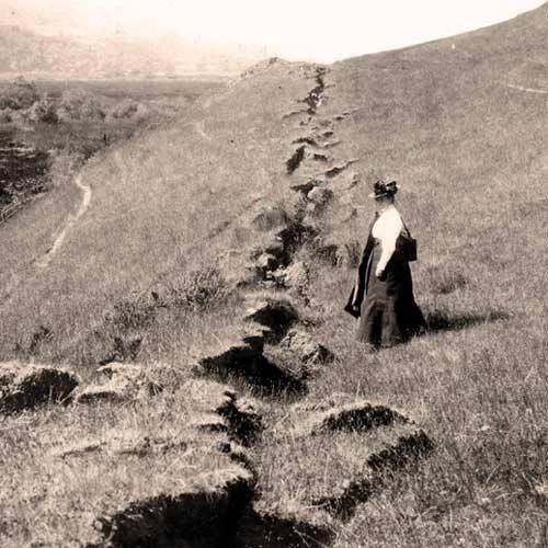 In an old photograph, Eastwood views a fault line crack in a grassy hill. 