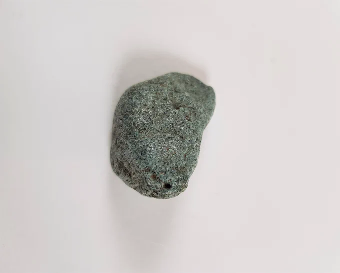 Een groen stuk plastic dat de vorm en structuur heeft van een kiezelsteen.
