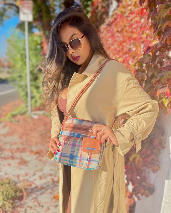 elegantly_saassy stands on the sidewalk in a beige rain coat with her #plaid and pecan North South Zip Around #Crossbody Bag.