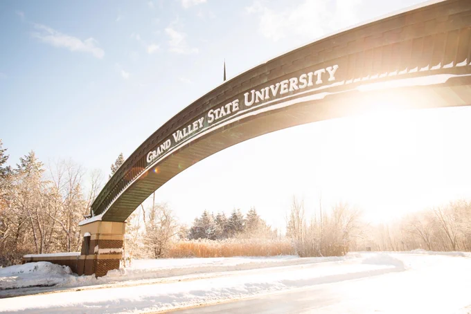 Image of the arch at the entrance of campus. The ground is snow covered.